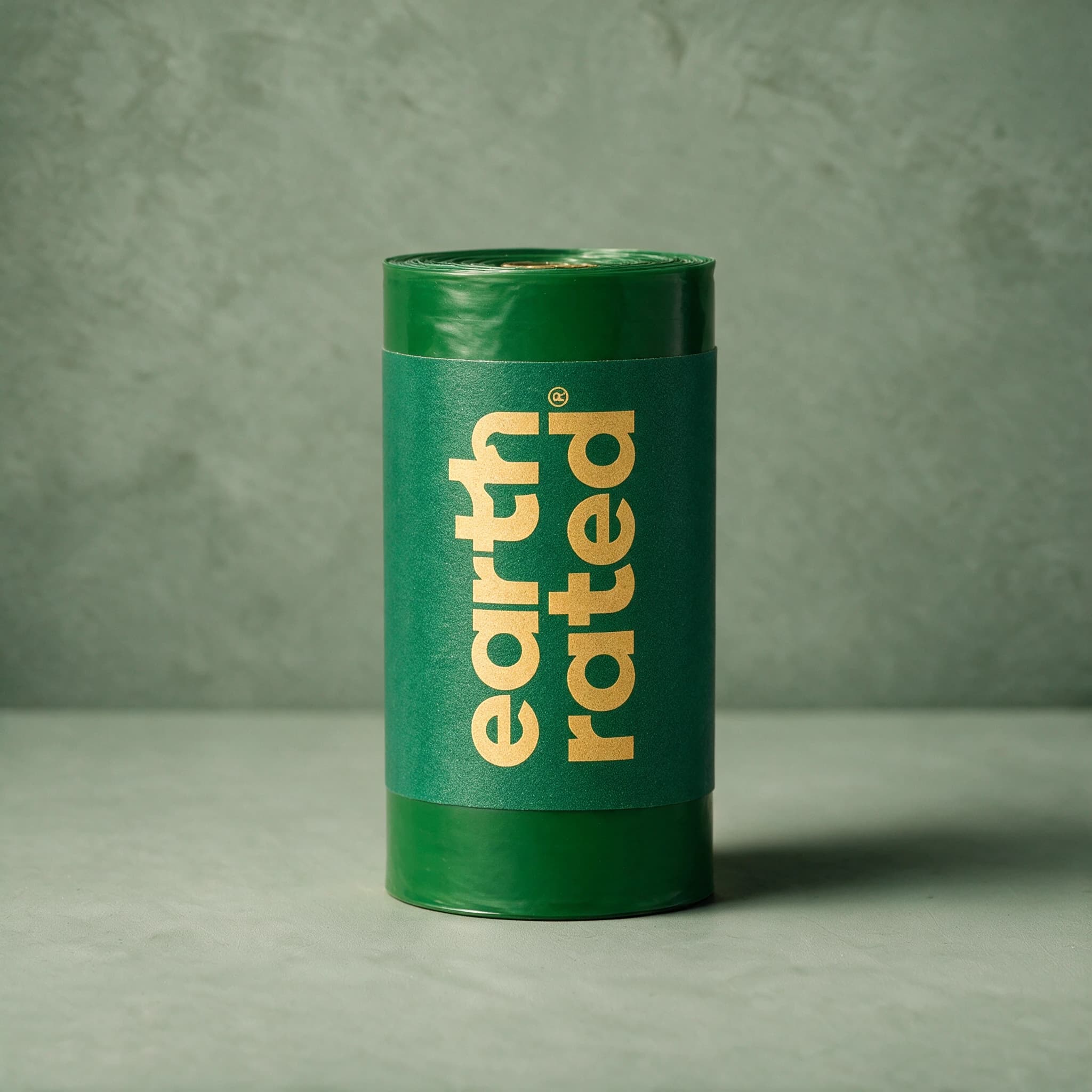 A single loose refill roll of Earth Rated poop bags, shown unpackaged against a sage green background.