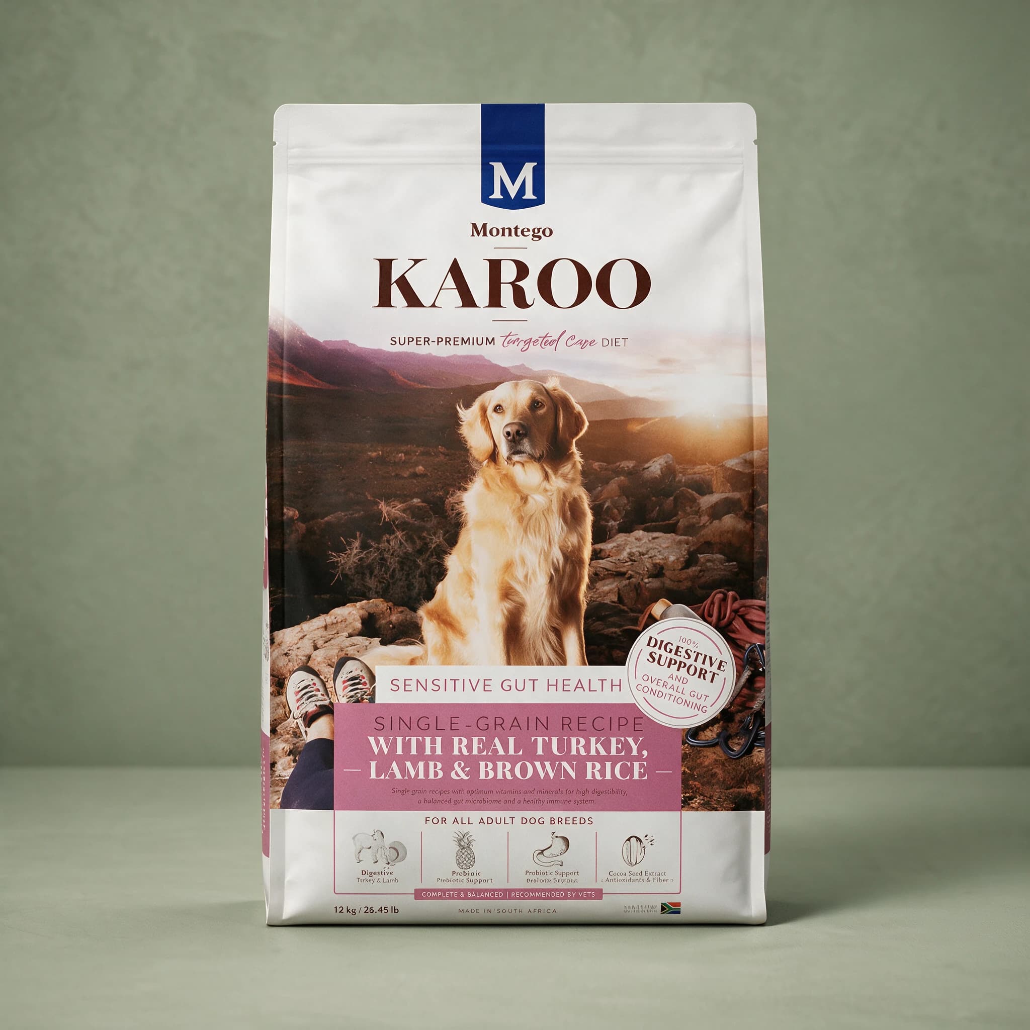 The white Montego Karoo "Targeted Care Diet" dry dog food bag, showing a Golden Retriever sitting on rocky terrain at sunset beside a person's hiking shoes and climbing rope, a "100% DIGESTIVE SUPPORT AND OVERALL GUT CONDITIONING" badge, a mauve "SENSITIVE GUT HEALTH — SINGLE-GRAIN RECIPE WITH REAL