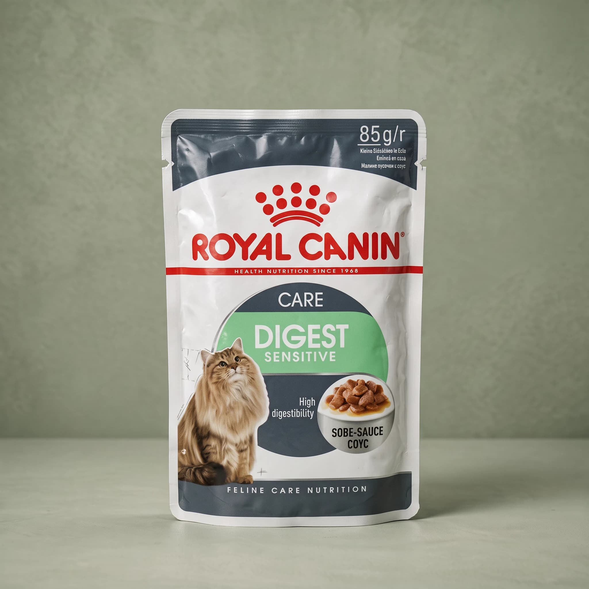 A grey and white Royal Canin Digest Sensitive wet cat food pouch with the red crown logo, standing upright against a plain sage green studio background.