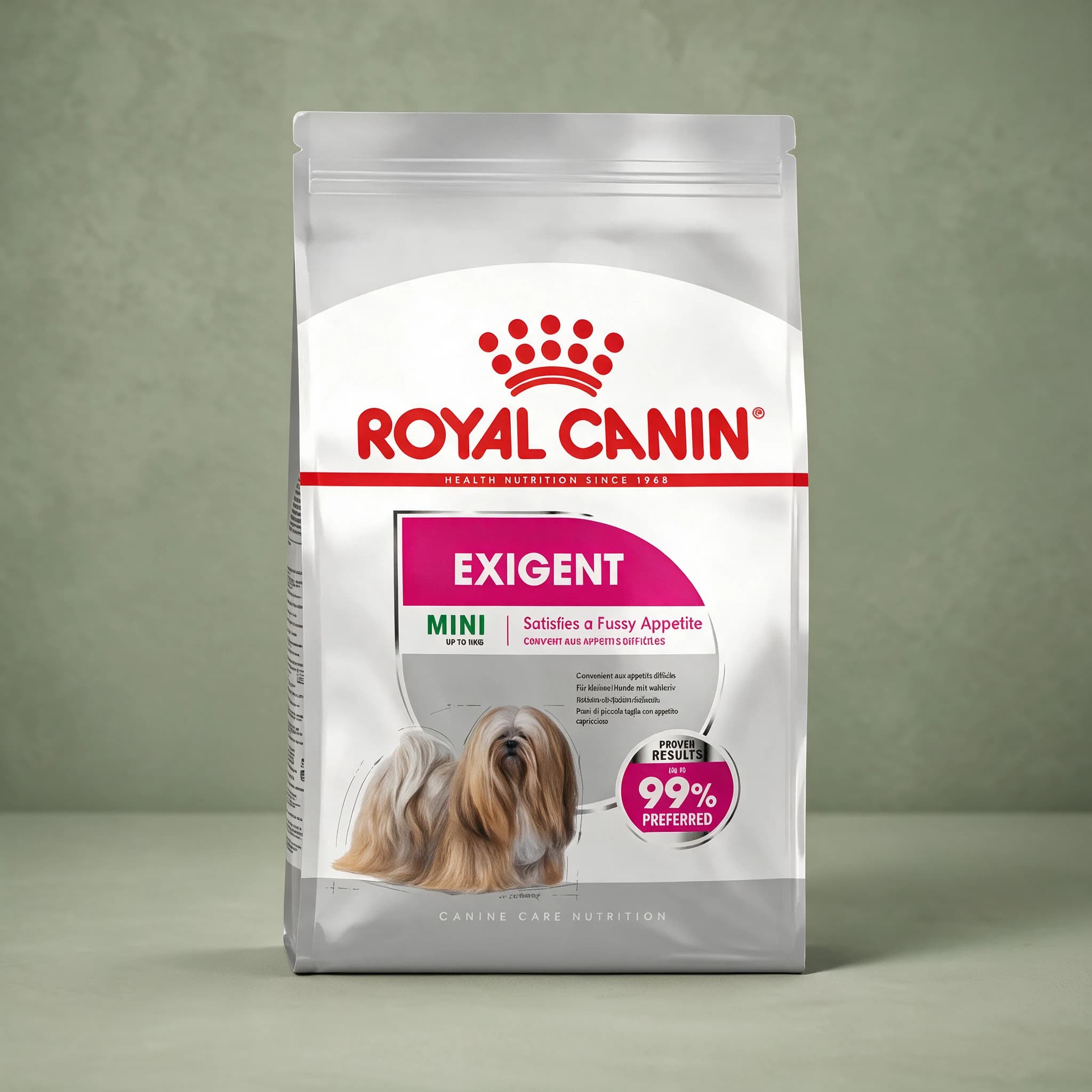 A white and grey Royal Canin bag labeled "Exigent Mini" for small, fussy-eating adult dogs, standing upright against a sage green studio background.