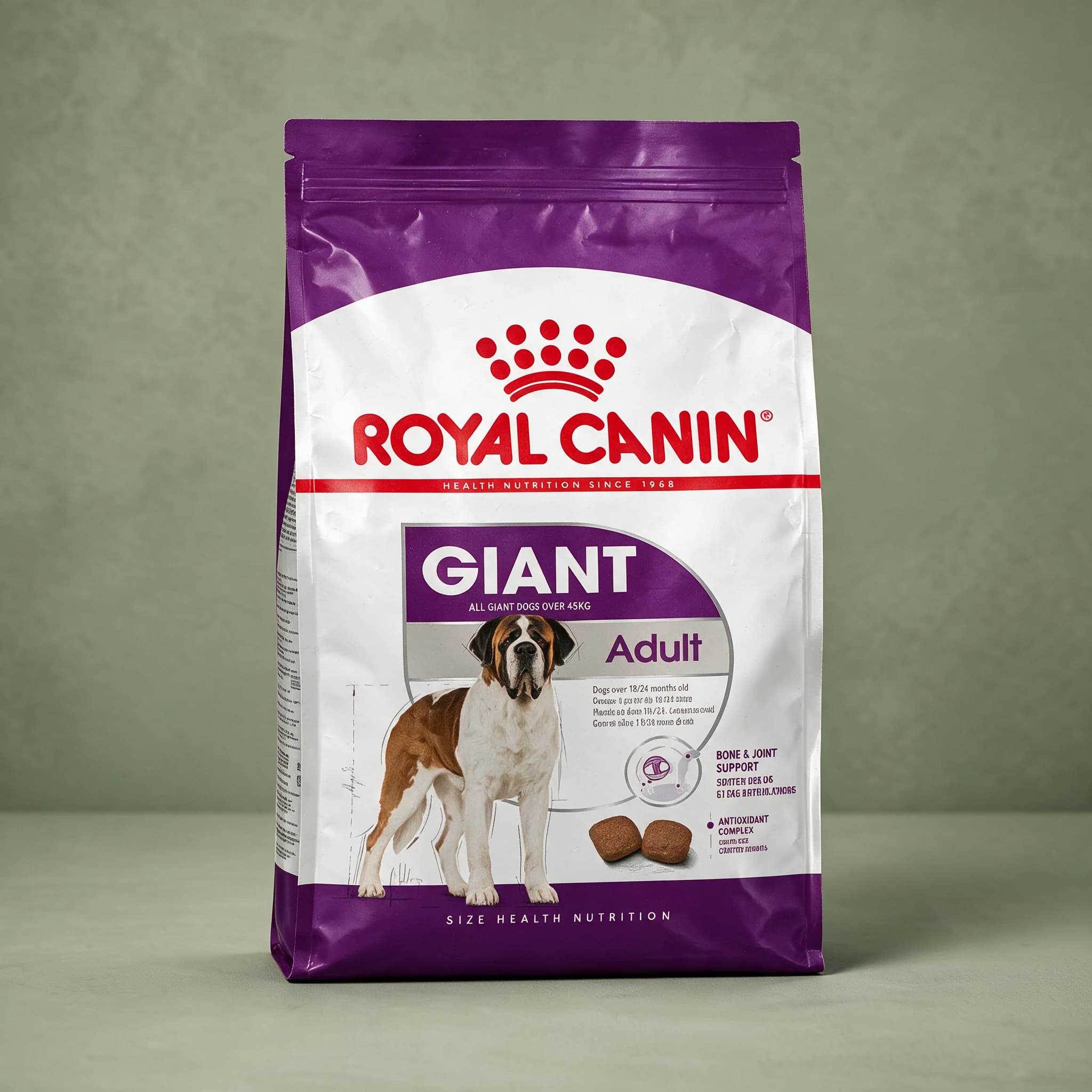 A grey and white Royal Canin dry dog food bag with the red crown logo, labeled "Adult Giant" for dogs with an adult weight over 45kg, photographed standing upright against a plain sage green studio background.
