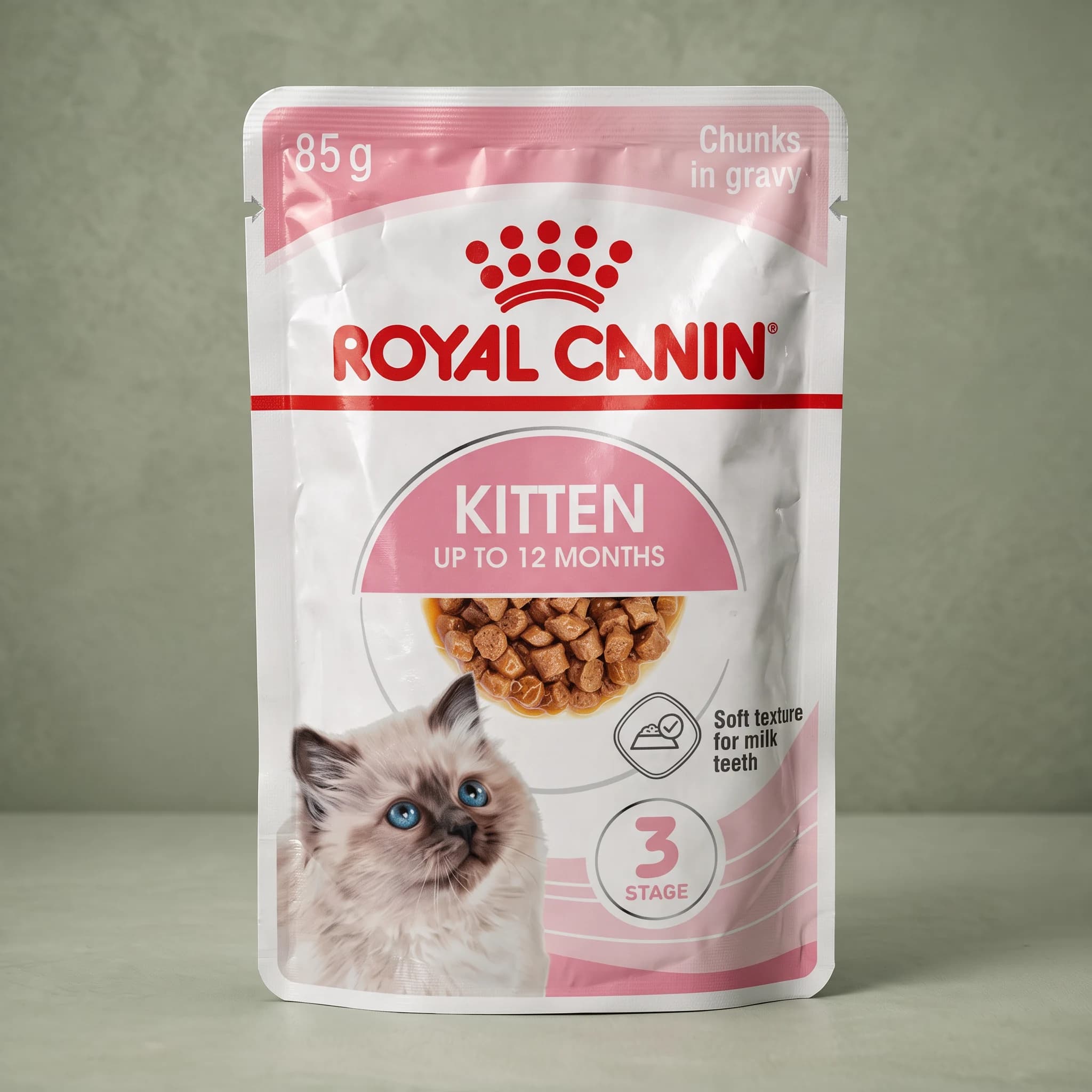 A Royal Canin Instinctive Kitten wet cat food pouch with the red crown logo and a kitten illustration, standing upright against a plain sage green studio background.