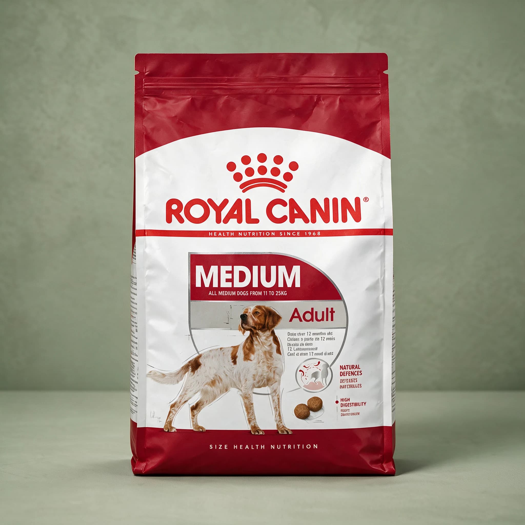 The blue and white Royal Canin Medium Adult dry dog food bag with the red crown logo, labeled "MEDIUM ADULT" with a medium-breed adult dog illustration, photographed against a plain sage green studio background.
